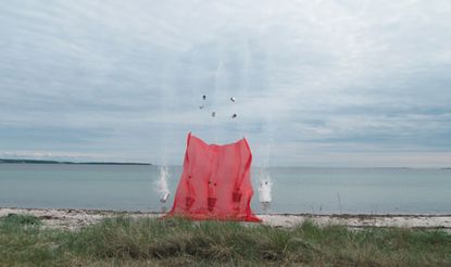 explosives with 50 metres of red Kvadrat fabric attached to the end over the sea