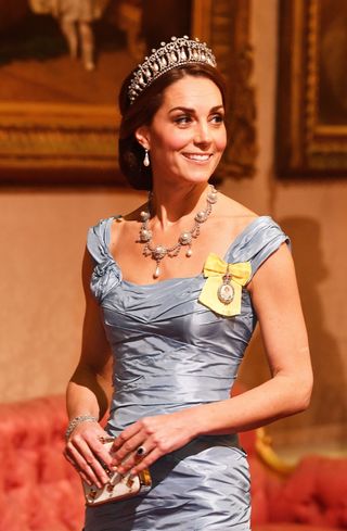 Kate Middleton looking to the right and smiling while wearing a baby blue evening gown and pearl necklace with a pearl-and-diamond tiara