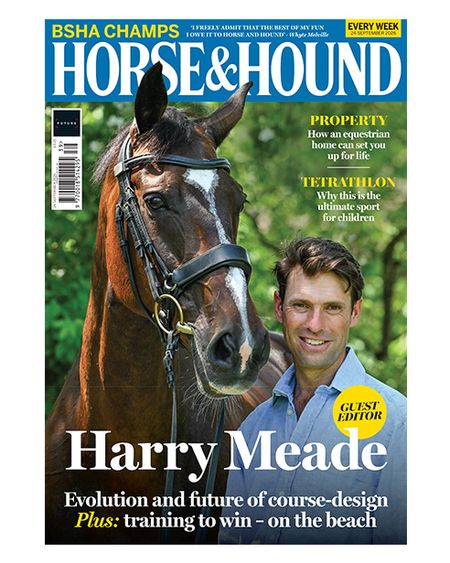 Harry Meade wears a blue shirt looking at the camera while standing beside a bay horse with white face markings wearing a snaffle bridle on the cover of Horse & Hound magazine, 24 September issue