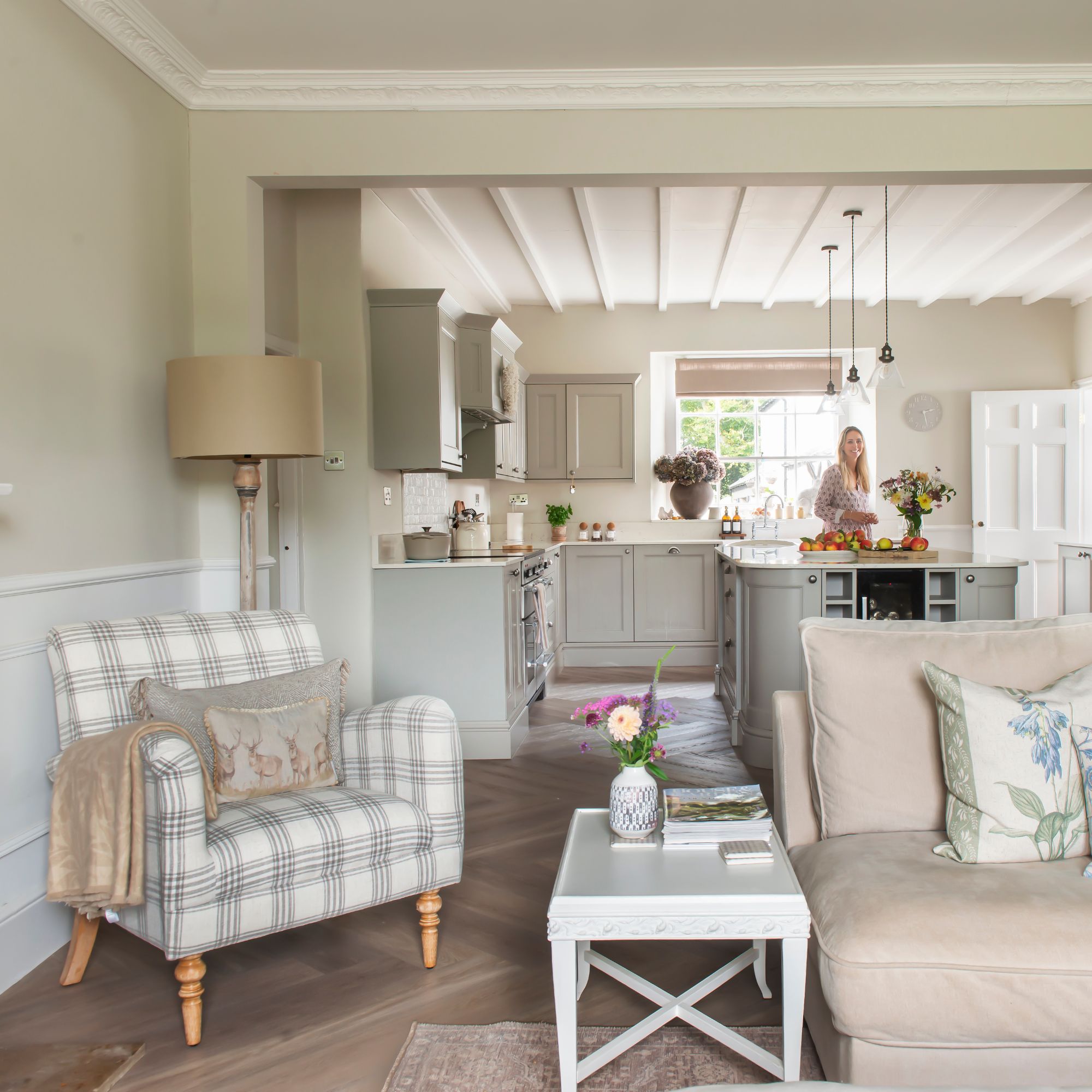 Living room through to kitchen in cottage with neutral interiors - grey kitchen with white worktops, striped armchair and pale sofa