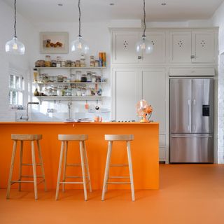 best colour combinations, orange and white kitchen with white walls, orange island and matching floor, bar stools, open shelving, white cabinetry, glass pendant lights