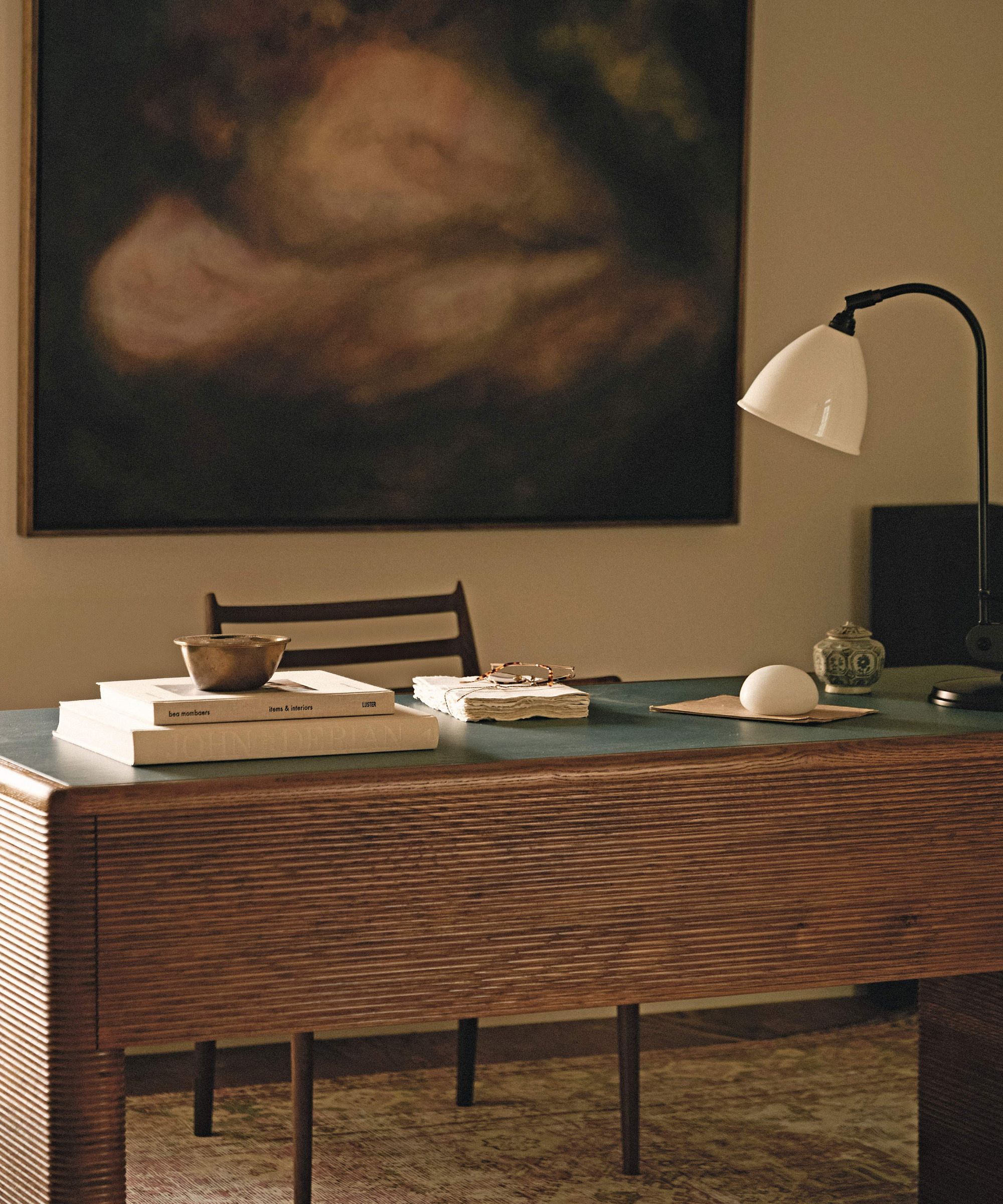 an earthy home office with large moody abstract art and fluted wooden desk
