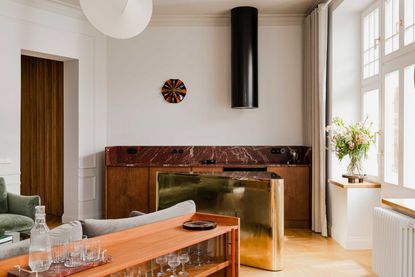 an open plan apartment with a brass triangular kitchen island