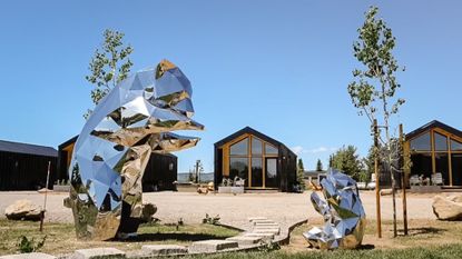 Two shiny bear statues in front of black cabins at Yellowstone Peaks in Idaho