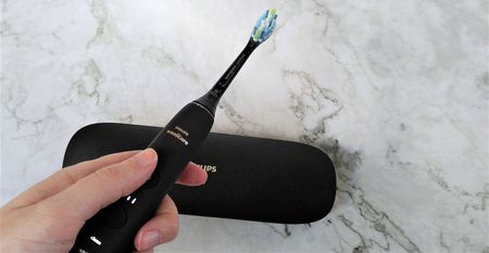 Woman holding Philips Sonicare 9000 DiamondClean electric toothbrush