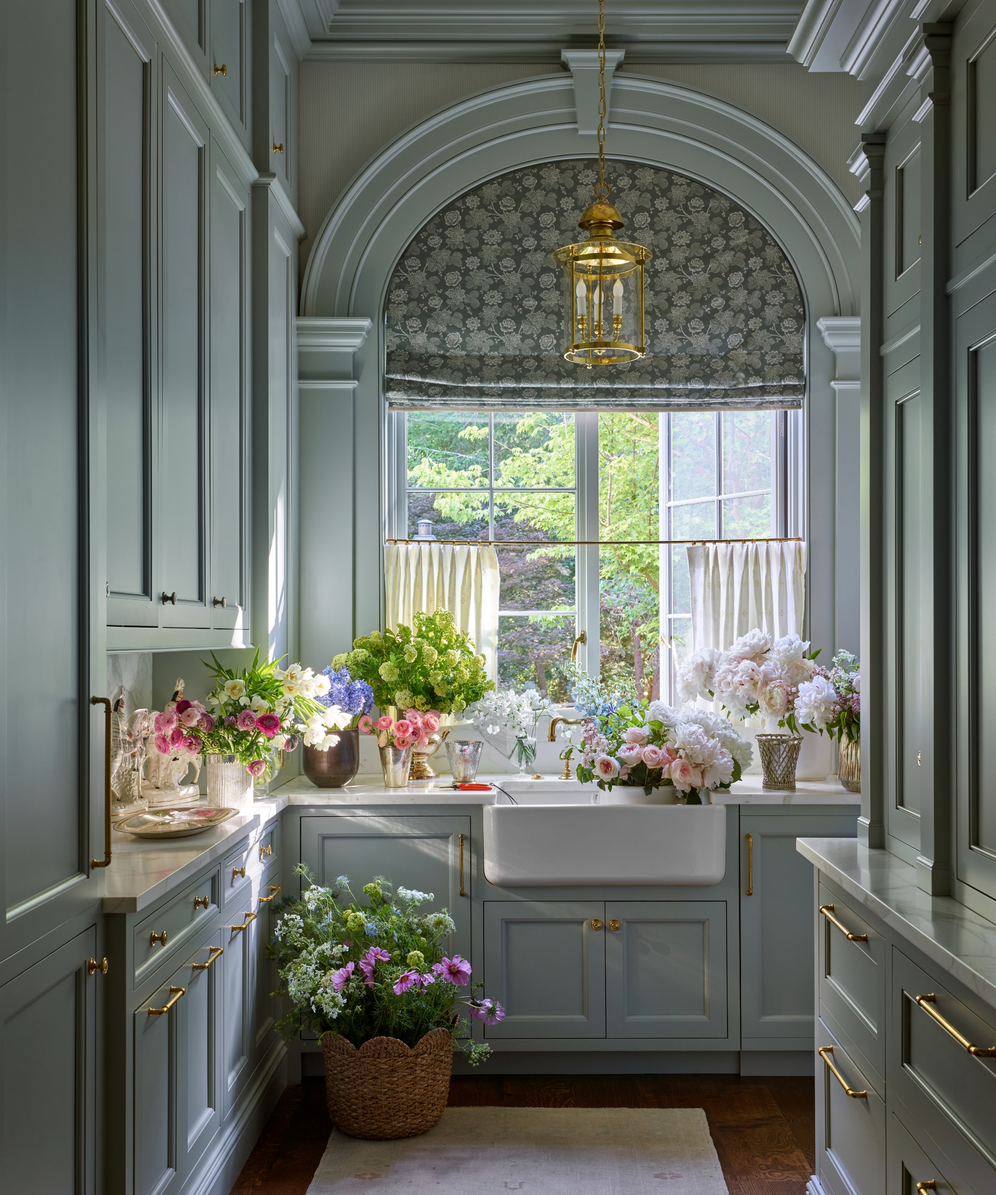 A blue butler's pantry with tall ceilings, shaker cabinets, and arched details