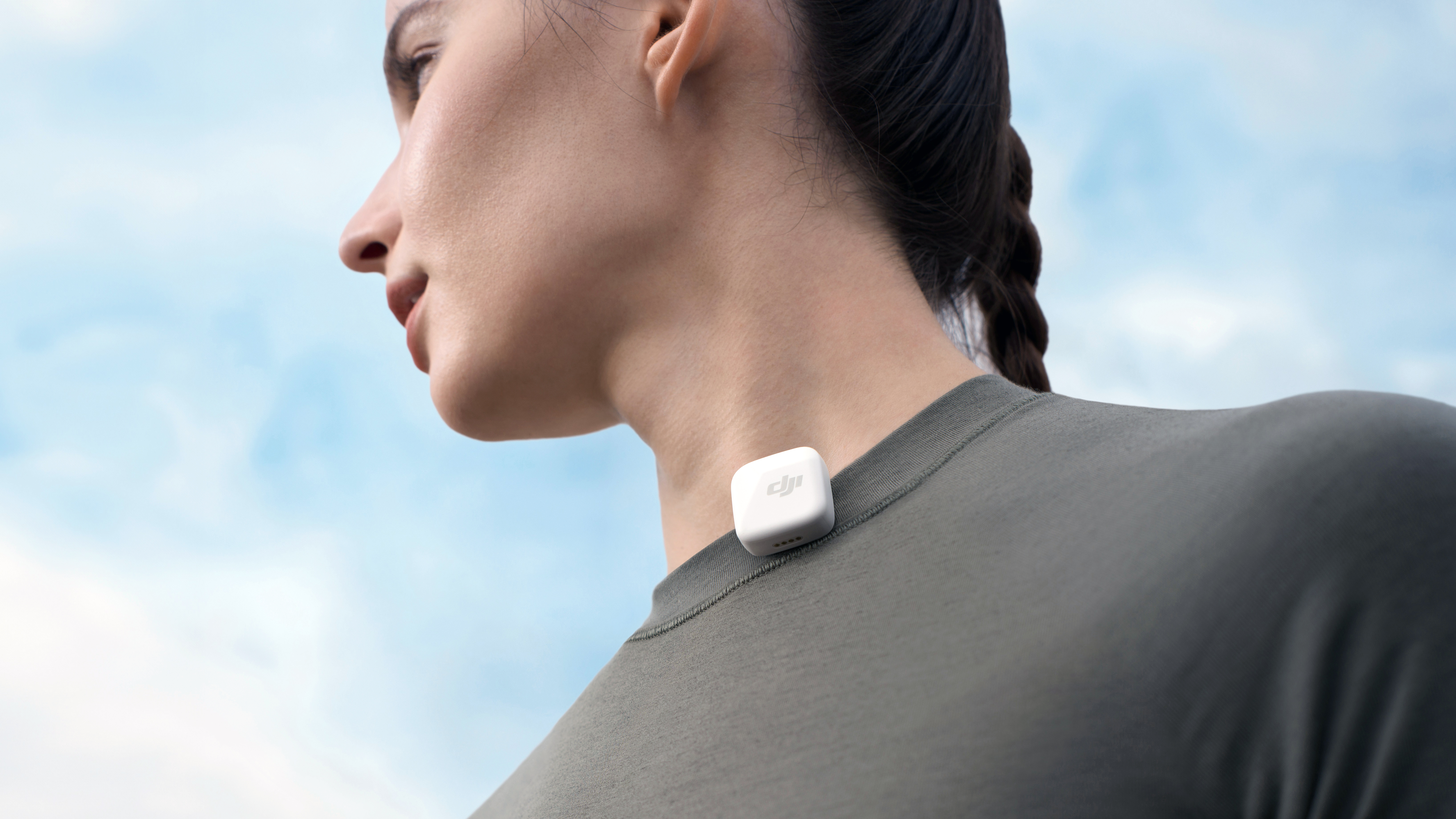 White DJI Mic Mini transmitter attached to a women's collar with sky background