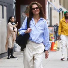 Katie Holmes wears a blue shirt with cream trousers.