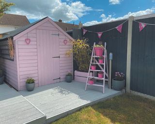 grey painted fence with a pale pink shed and light grey decking