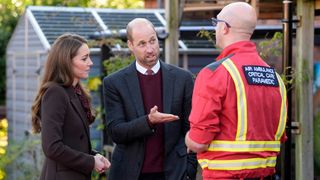 Prince William, Prince of Wales and Catherine, Princess of Wales speak to a member of the emergency services during a visit to Southport Community Centre