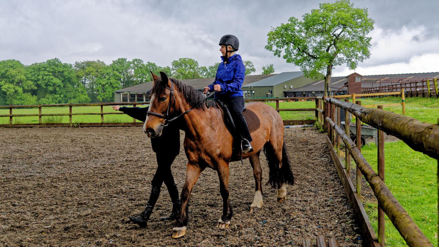 Pictured a person having a riding lesson at a riding school.