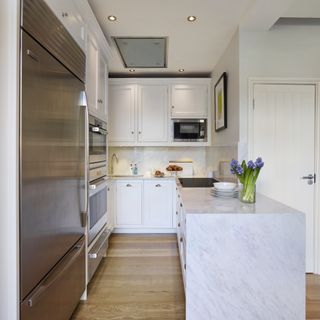 White narrow kitchen with marble island