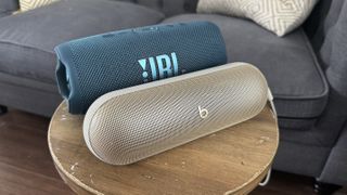 Beats Pill and JBL Charge 5 sitting on a table