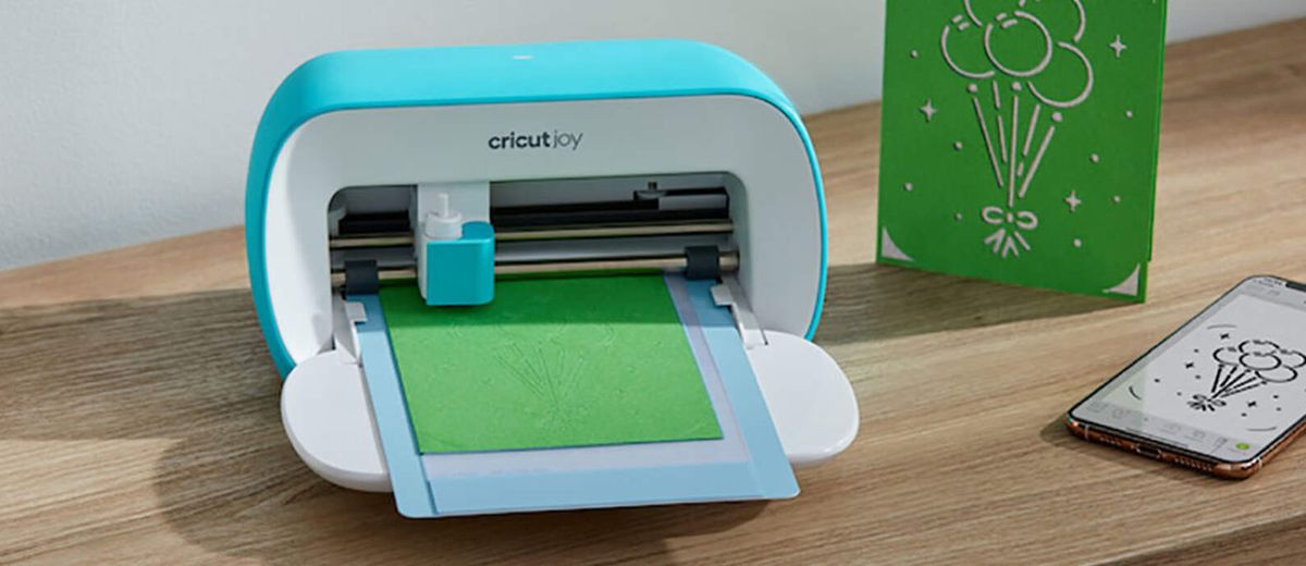 Cricut Joy review; a small craft cutting machine on a wooden table with home made cards