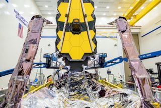 Technicians examine the 6.5-meter segmented primary mirror and deployable sunshield of the James Webb Space Telescope, NASA's $10-billion “flagship” observatory, which is scheduled to launch in November.