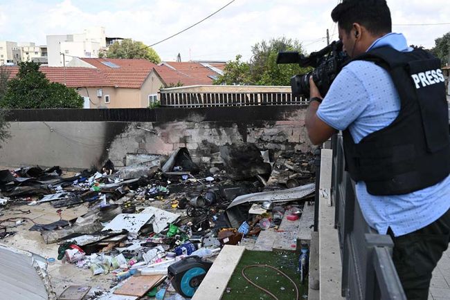 A journalist inspects the site of a missle strike in Sdereot, Israel. 