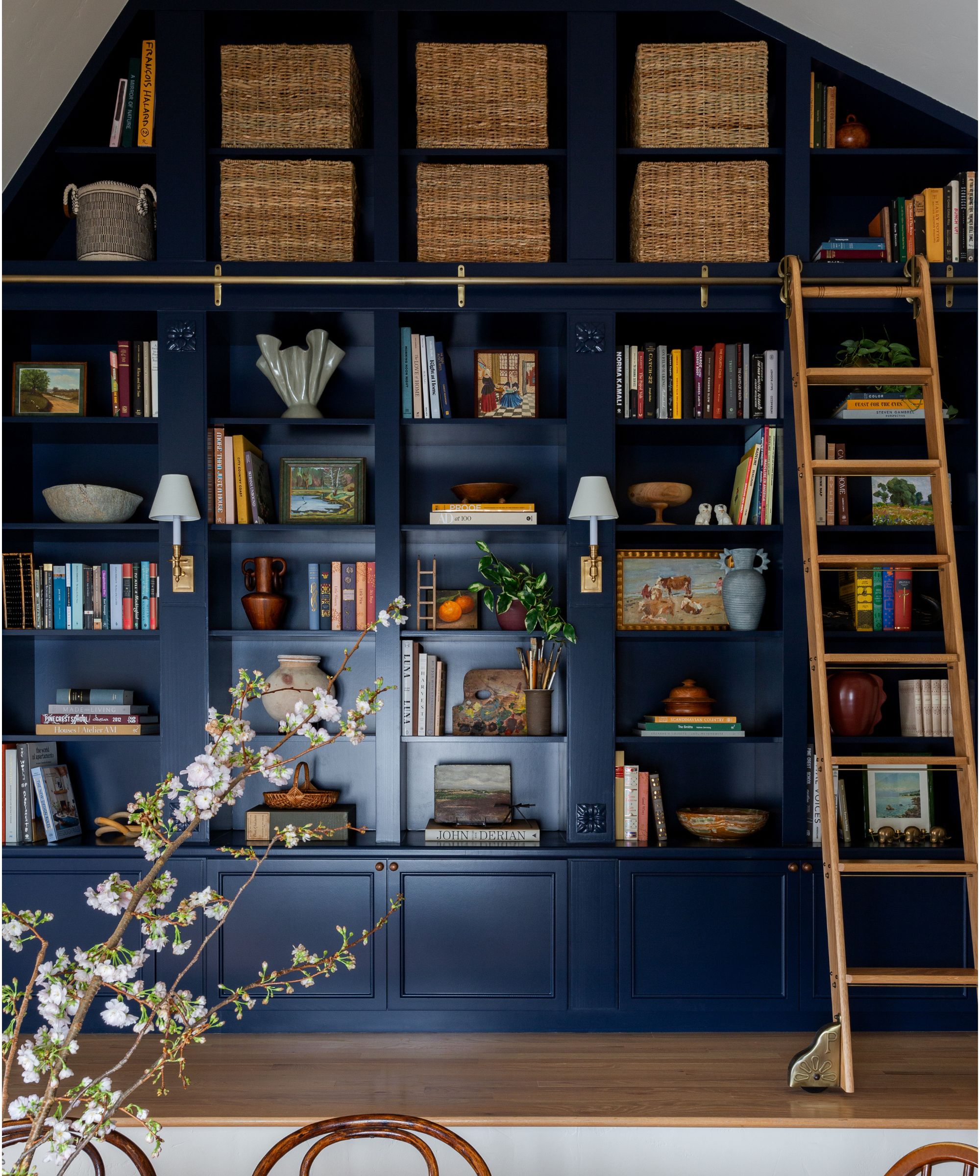 a 30-foot library wall painted dark blue with a wooden library ladder
