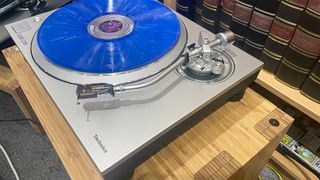 Technics SL-1300G turntable on wooden hi-fi rack top-down side angle with blue vinyl on platter