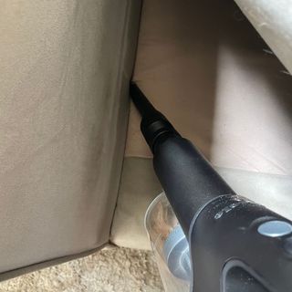 Using the Miele DuoFlex crevice tool down the side of a beige sofa