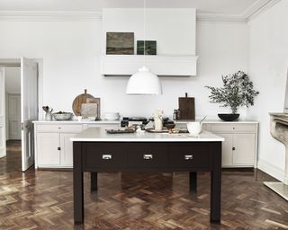 A traditional white kitchen with statement pendant light over a black painted island.