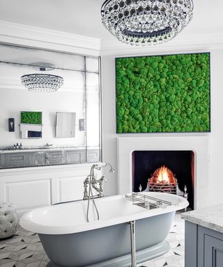 A white bathroom with a gray roll top bath in front of a fire