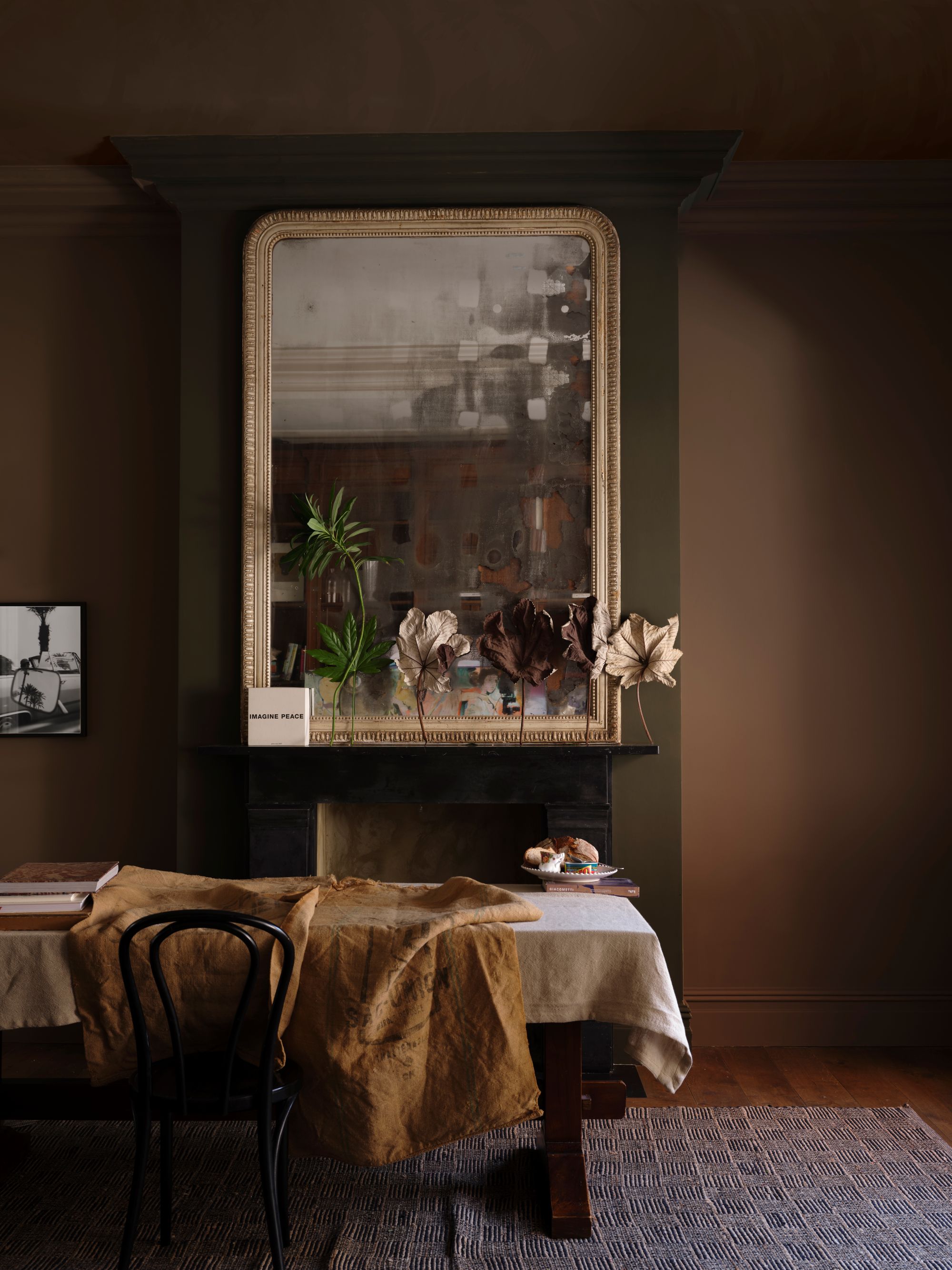 a brown dining room with a large table covered with a table cloth and a fire place with a mantle and a large mirror
