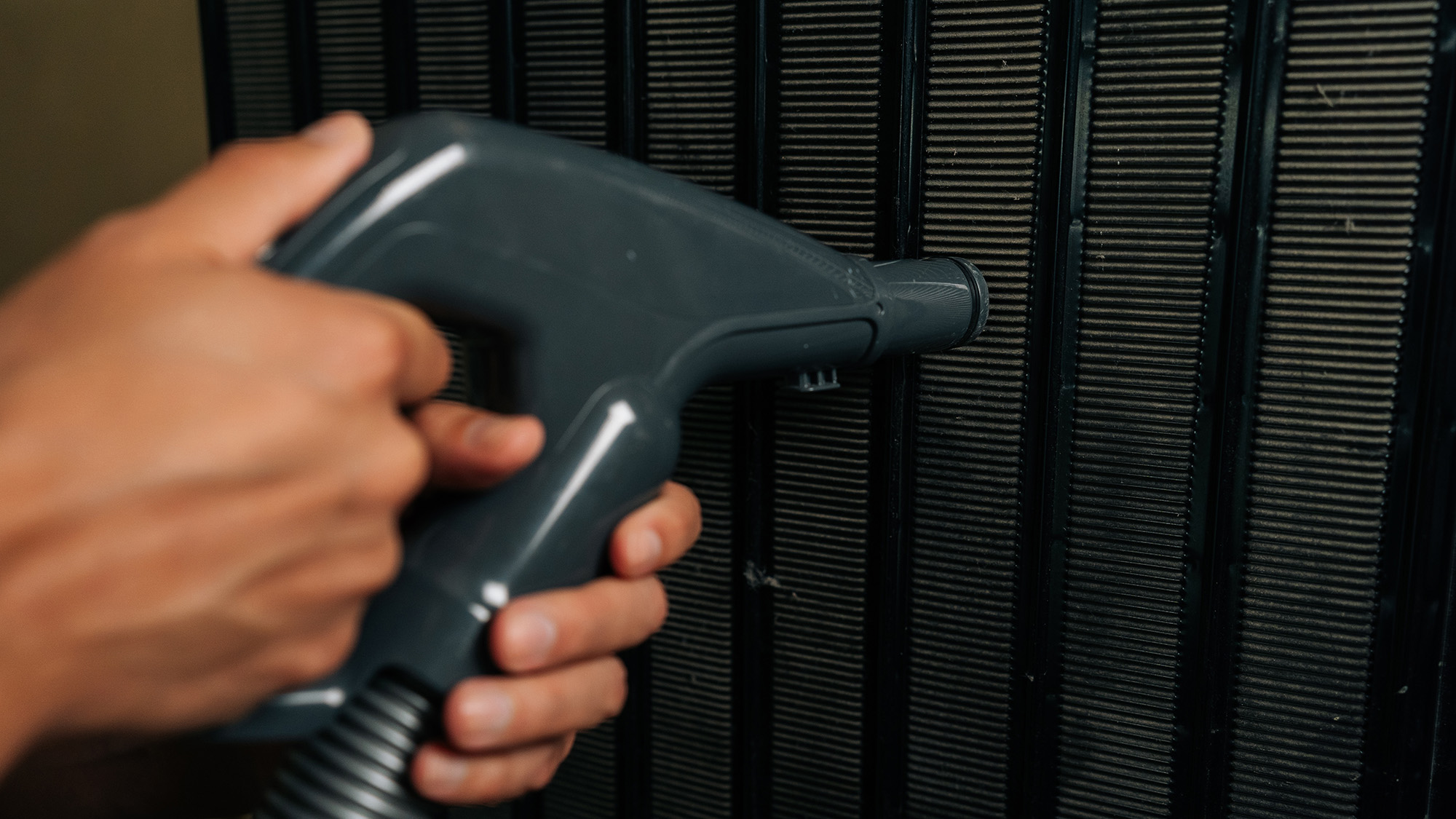 Man vacuuming back of refrigerator coils
