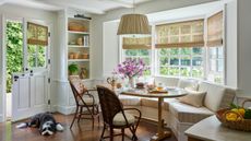 The end of a white kitchen with a large striped banquette installed into a bay window