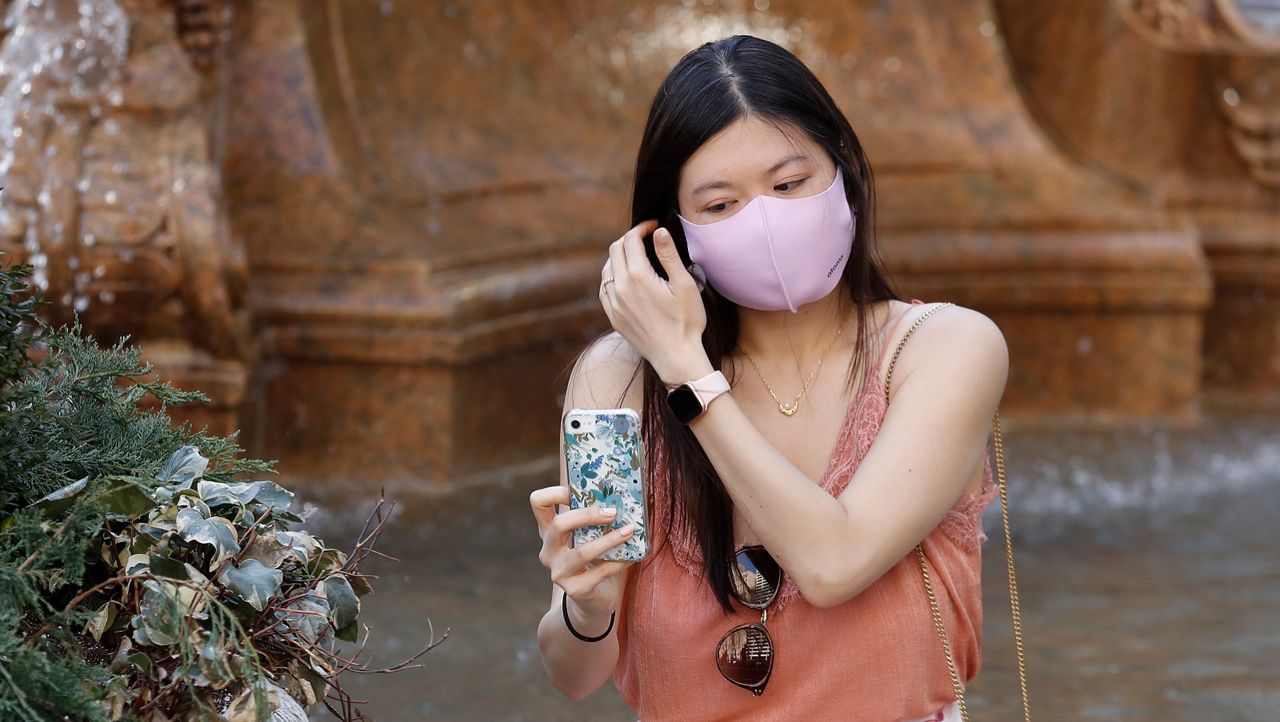 A woman wearing a protective mask looks at her cell phone in Bryant Park on March 26, 2021 in New York City.