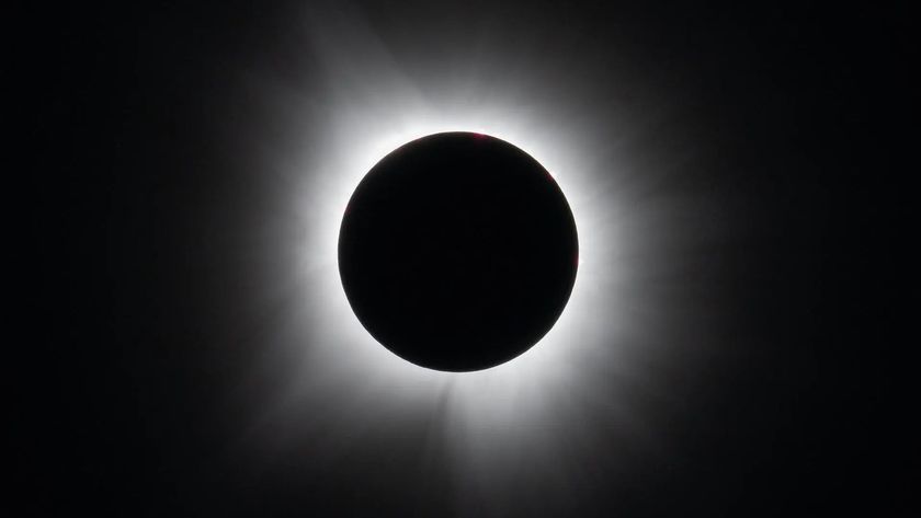 A black circle against a black background surrounded by white wispy tendrils