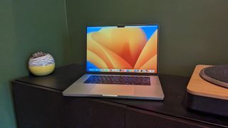 MacBook Pro 16-inch (2023) on wooden desk with green background