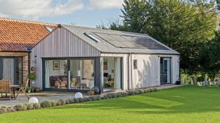 A single storey pitched roof extensionclad in timber attached to a red brick dwelling