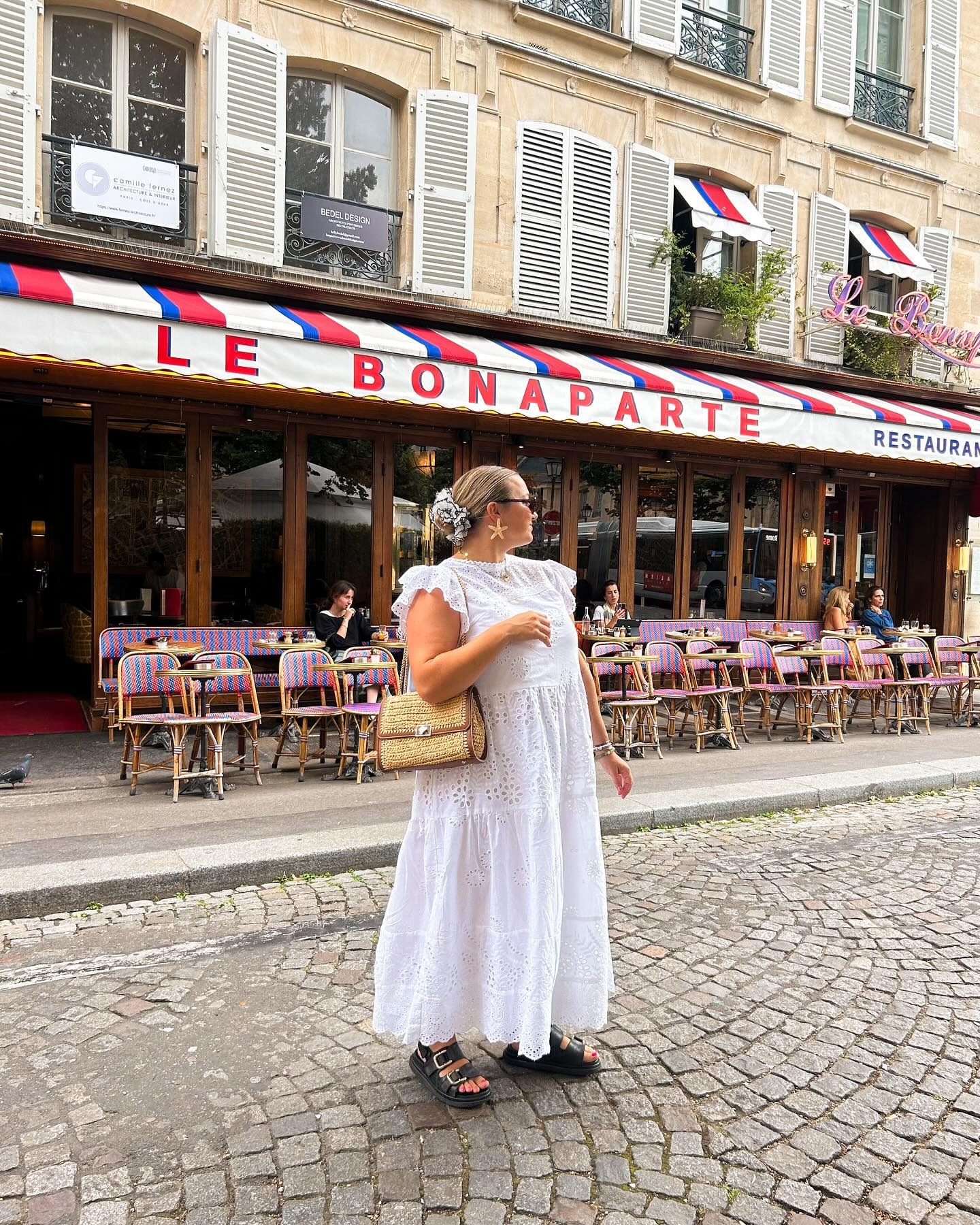 Influencer @hannahfgale wears a white maxi broderie anglaise dress with a wicker shoulder bag.