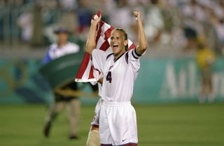 Carla Overbeck #4 of the USA Team carries the flag as she celebrates after winning the Woman's Soccer Final against the China Team during the 1996 Olympic Games at the Sanford Stadium on August 1,1996 in Athens, Georgia. The USA defeated China 2-1. (Photo by: David Cannon /Getty Images)