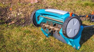 Electric lawn aerator, raised up to reveal blades and spikes