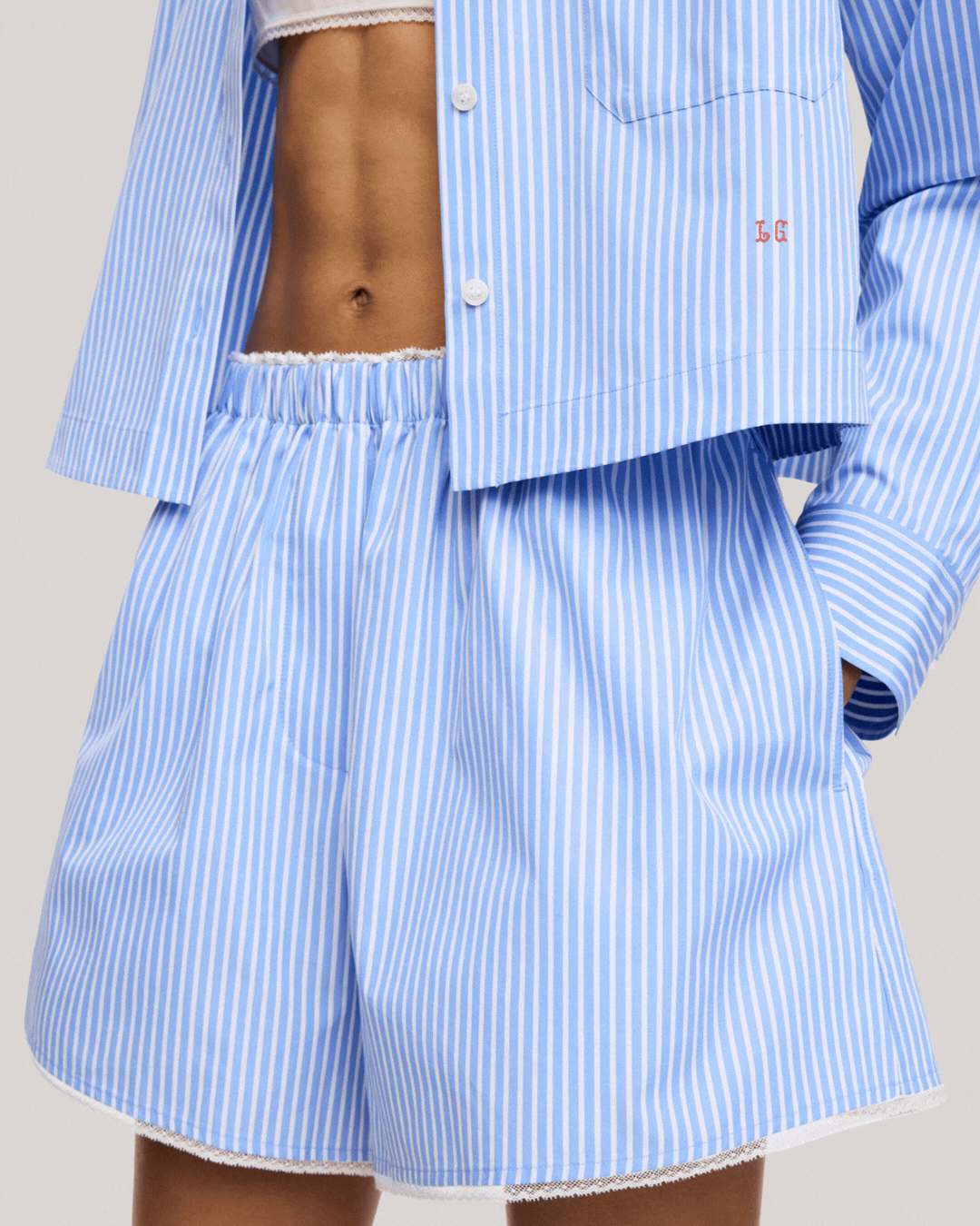 ARKET and Laila Gohar Lace-Trim Shorts, shown as worn by a model against a pale brown background in a rotating gif.