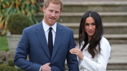 Britain's Prince Harry stands with his fiancée US actress Meghan Markle as she shows off her engagement ring whilst they pose for a photograph in the Sunken Garden at Kensington Palace in west London on November 27, 2017, following the announcement of their engagement. - Britain's Prince Harry will marry his US actress girlfriend Meghan Markle early next year after the couple became engaged earlier this month, Clarence House announced on Monday.