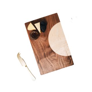 wood serving board with a brass knife on the left and cheese on the top left