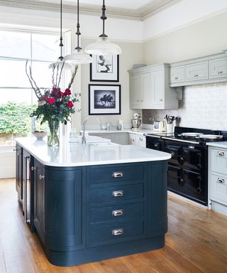 Classic U-shaped kitchen in a neutral scheme with dark blue and marble island.