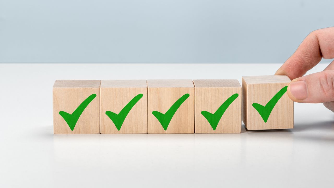 Five wooden blocks with green checkmarks on them are lined up.