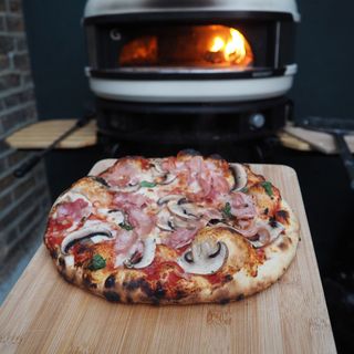 Finished cooked pizza in front of the Gozney Dome pizza oven