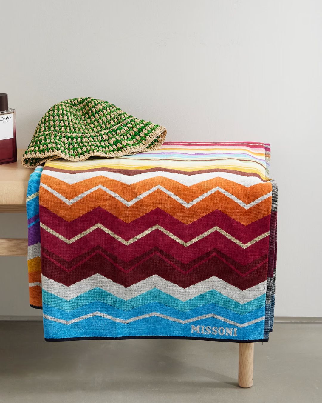 Hugo Striped Cotton-Terry Towel folded onto pale wood bench and topped by a knitted hat in green and neutral raffia.