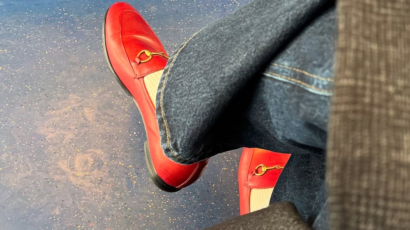 Photo of red Gucci loafers with butter yellow socks, dark straight jeans and a Tibi coat. 