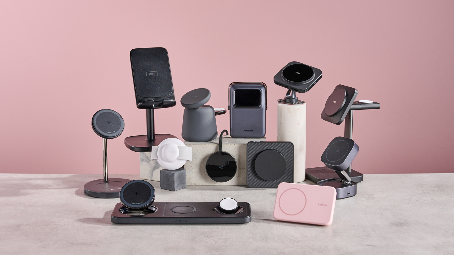 A collection of different wireless chargers are grouped together in the middle of a tabletop.