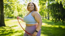 Woman standing in sunny park holding resistance band