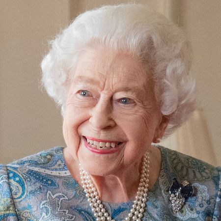 Queen Elizabeth wearing a blue dress and pearls smiling