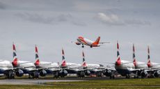 A fleet of British Airway planes sit on the runway at Glasgow Airport as an EasyJet plane takes off.