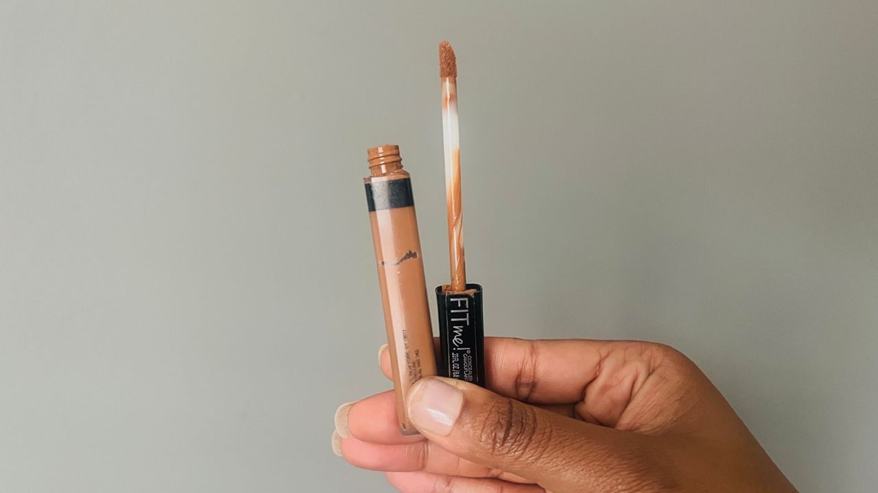 A person holding an opened Maybelline Fit Me Concealer for the best drugstore concealers.