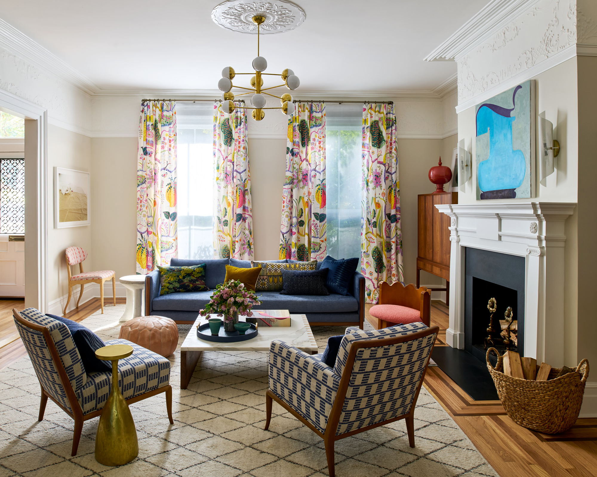 two twin chairs facing a sofa in a living room with colorful patterened curtains in front of the window behind the sofa