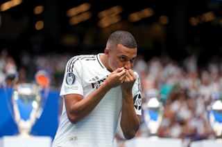 Kylian Mbappe kisses his Real Madrid shirt during his official presentation with Los Blancos at the Santiago Bernabeu in July 2024.